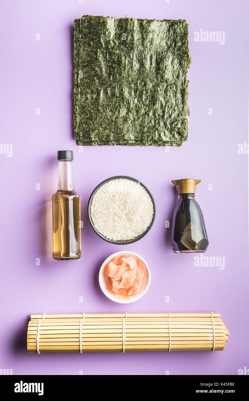 Il sushi ingredienti sulla tabella di colore viola. Riso, lo zenzero, la salsa di soia, aceto e nori fogli. Foto Stock