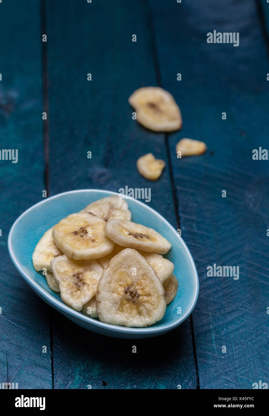 Banane essiccate in una ciotola sulla benzina di legno colorato sfondo. Foto Stock