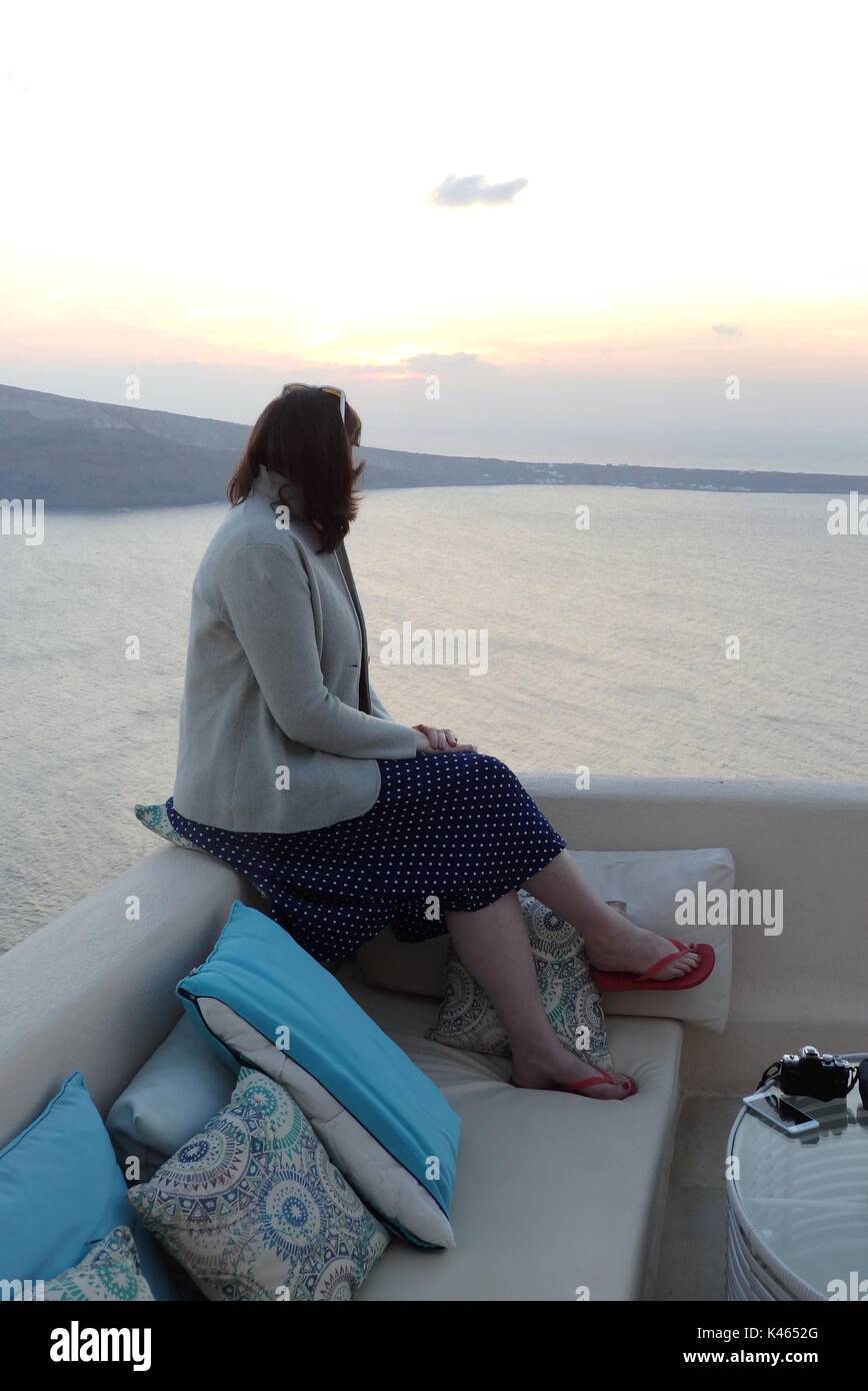 Signora guardando il tramonto di Oia - Santorini - uno dei mondi migliori destinazioni di viaggio per i tramonti Foto Stock