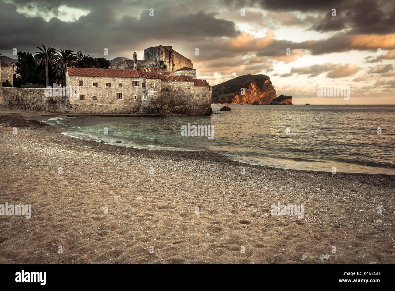 Comunità turistica di mare resort fort Budva con architettura medievale a Sunset Beach con drammatica sky in Europa paese Montenegro della penisola balcanica Foto Stock