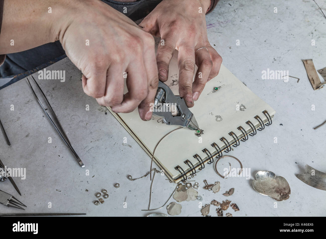 Gli occhi di uccello vista delle mani di un gioielliere femmina lavorando sul suo posto di lavoro. Foto Stock