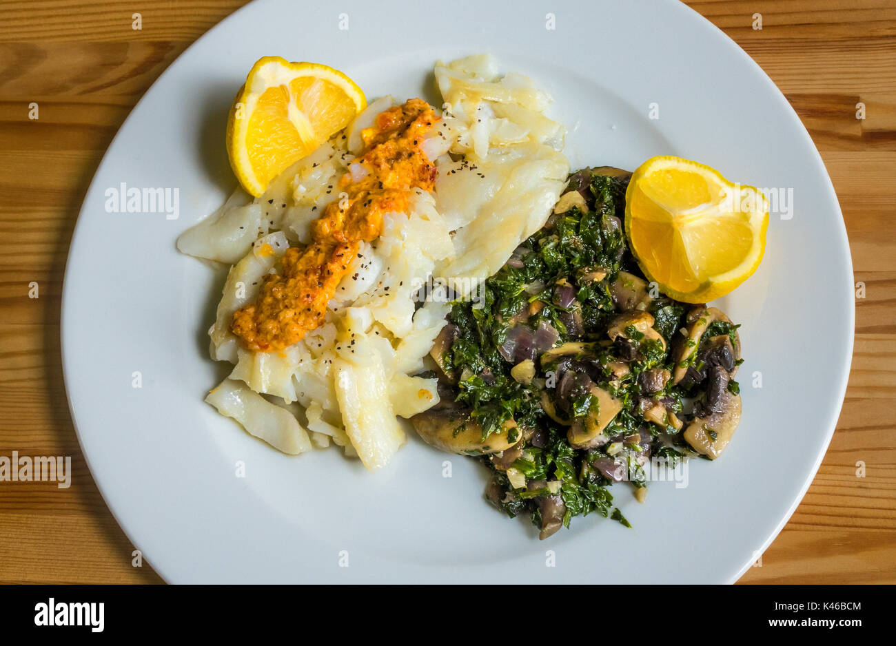 Di merluzzo, pesce bollito con spinaci, funghi, limone, burro e un tocco di salsa calda. Foto Stock