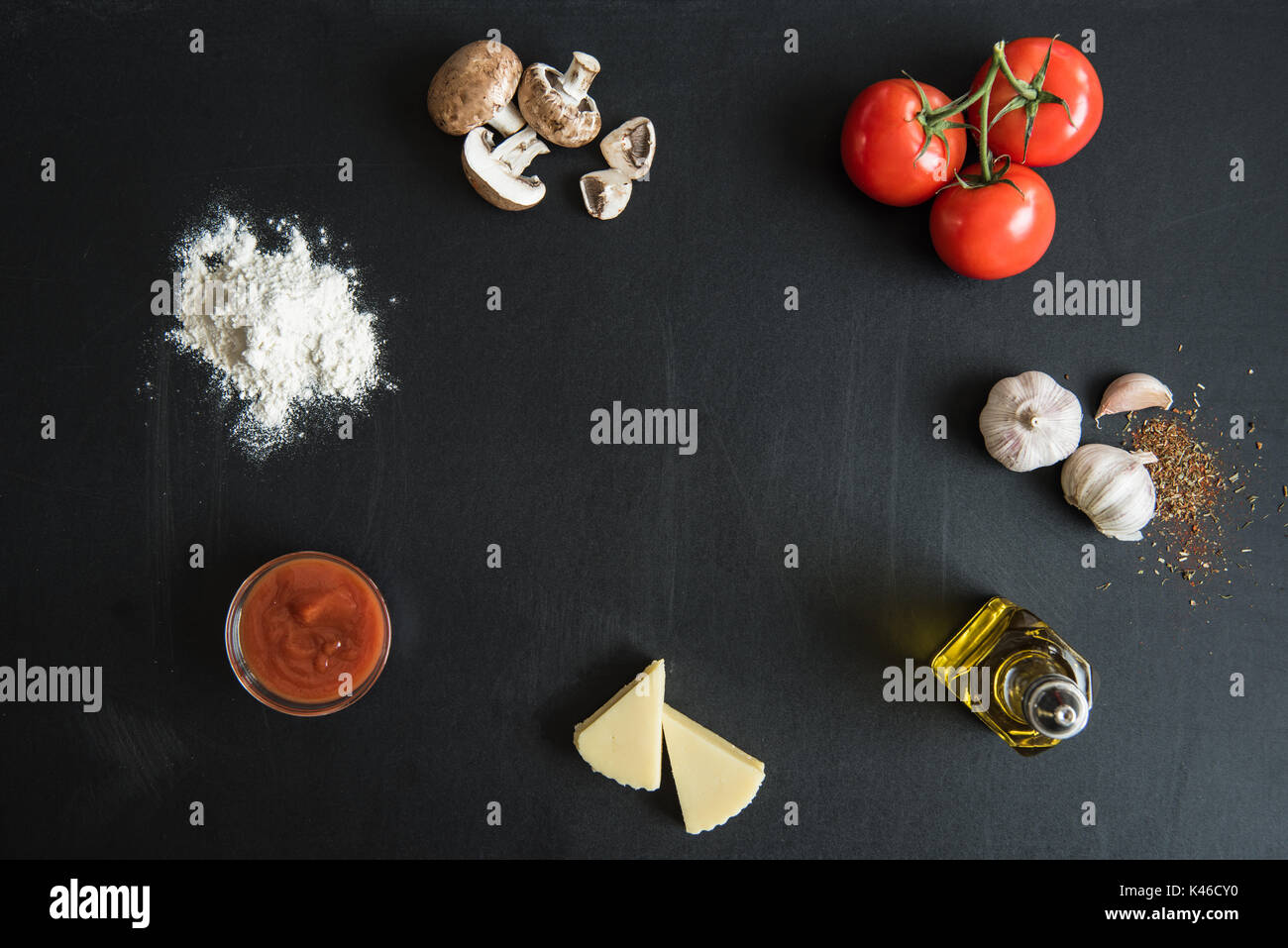 Vista superiore degli ingredienti per la preparazione di pizza italiana sulla superficie scura Foto Stock