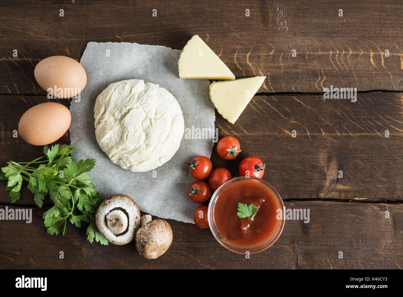 Vista superiore della pasta con gli ingredienti per la preparazione della pizza italiana sul piano portapaziente in legno Foto Stock