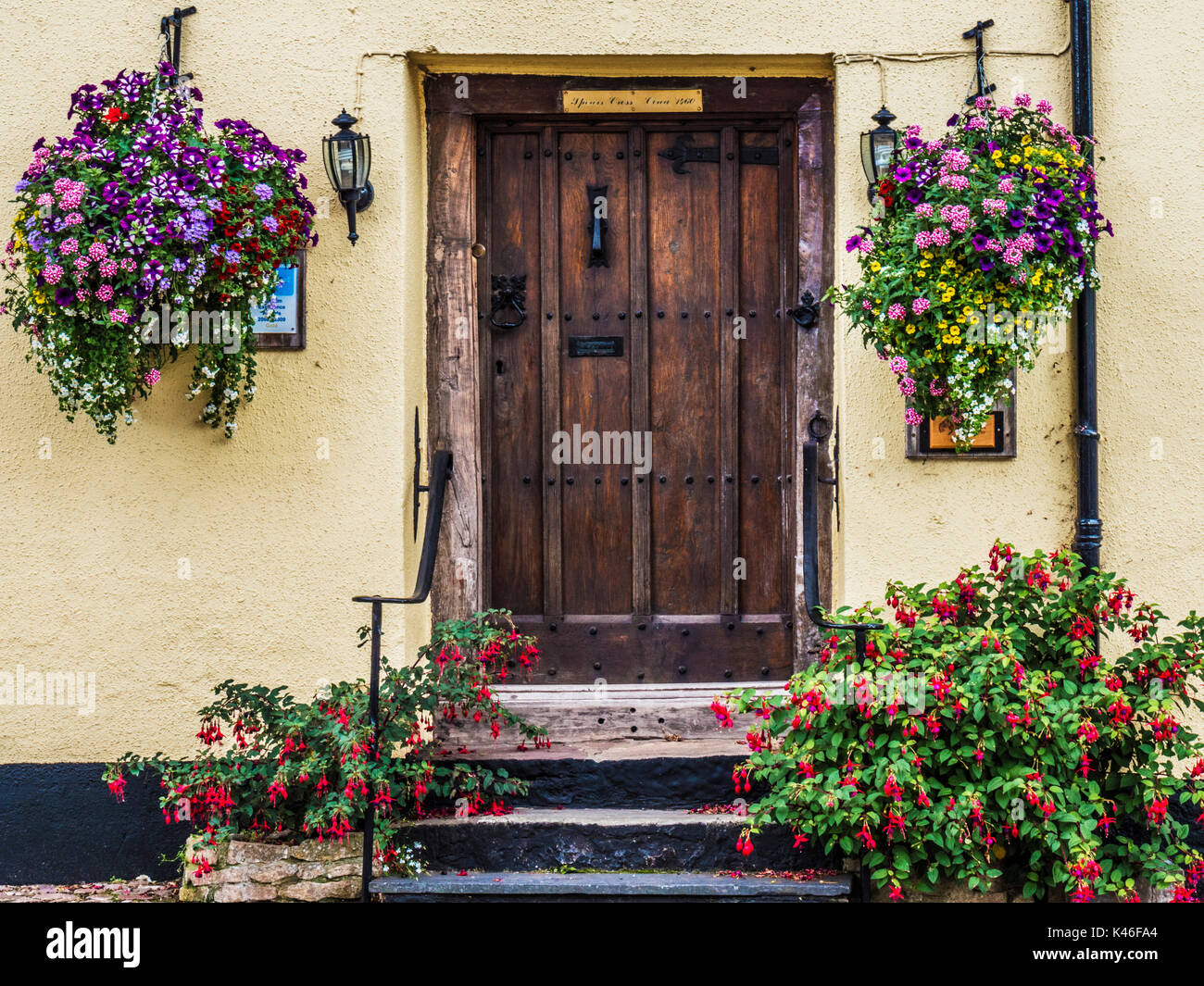 In legno antico porta anteriore circondato da fiori colorati in Dunster High Street vicino a Minehead, Somerset. Foto Stock