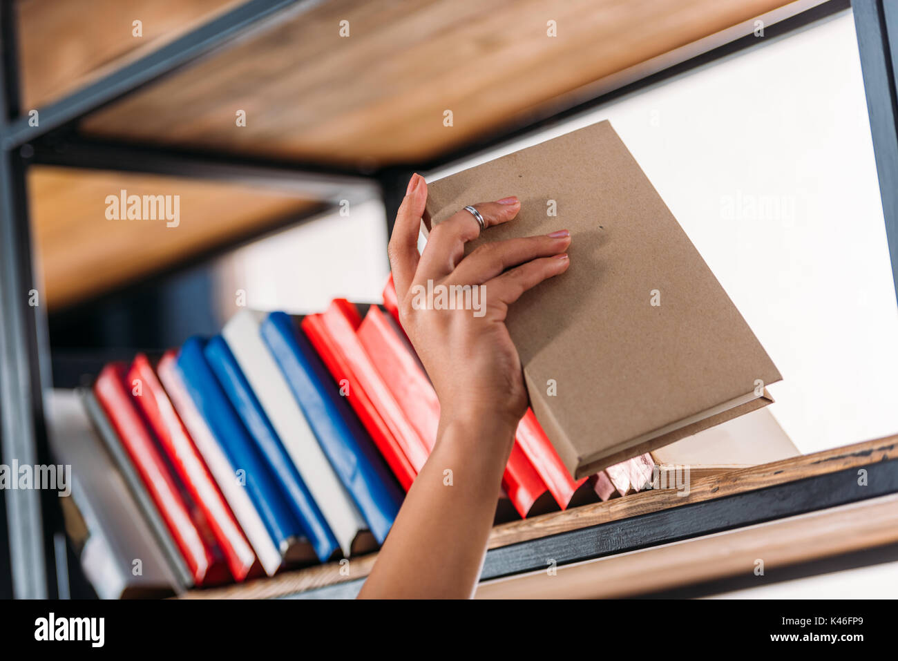 Ritagliato colpo di studente azienda prenota a scaffale in libreria Foto Stock