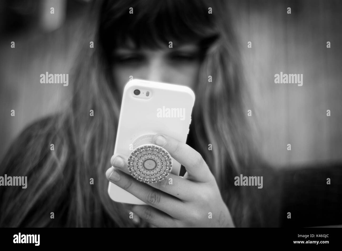 In bianco e nero di immagine fuori fuoco giovane ragazza che gioca su iphone Foto Stock