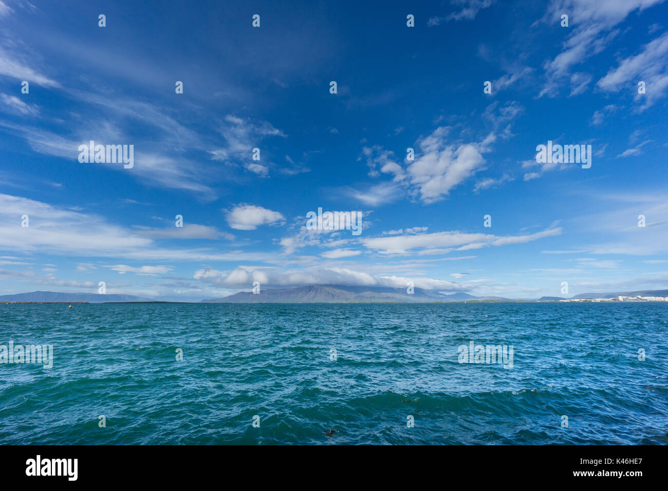 Islanda - acqua azzurra dell'oceano presso la costa della città di Reykjavik con montagne Foto Stock