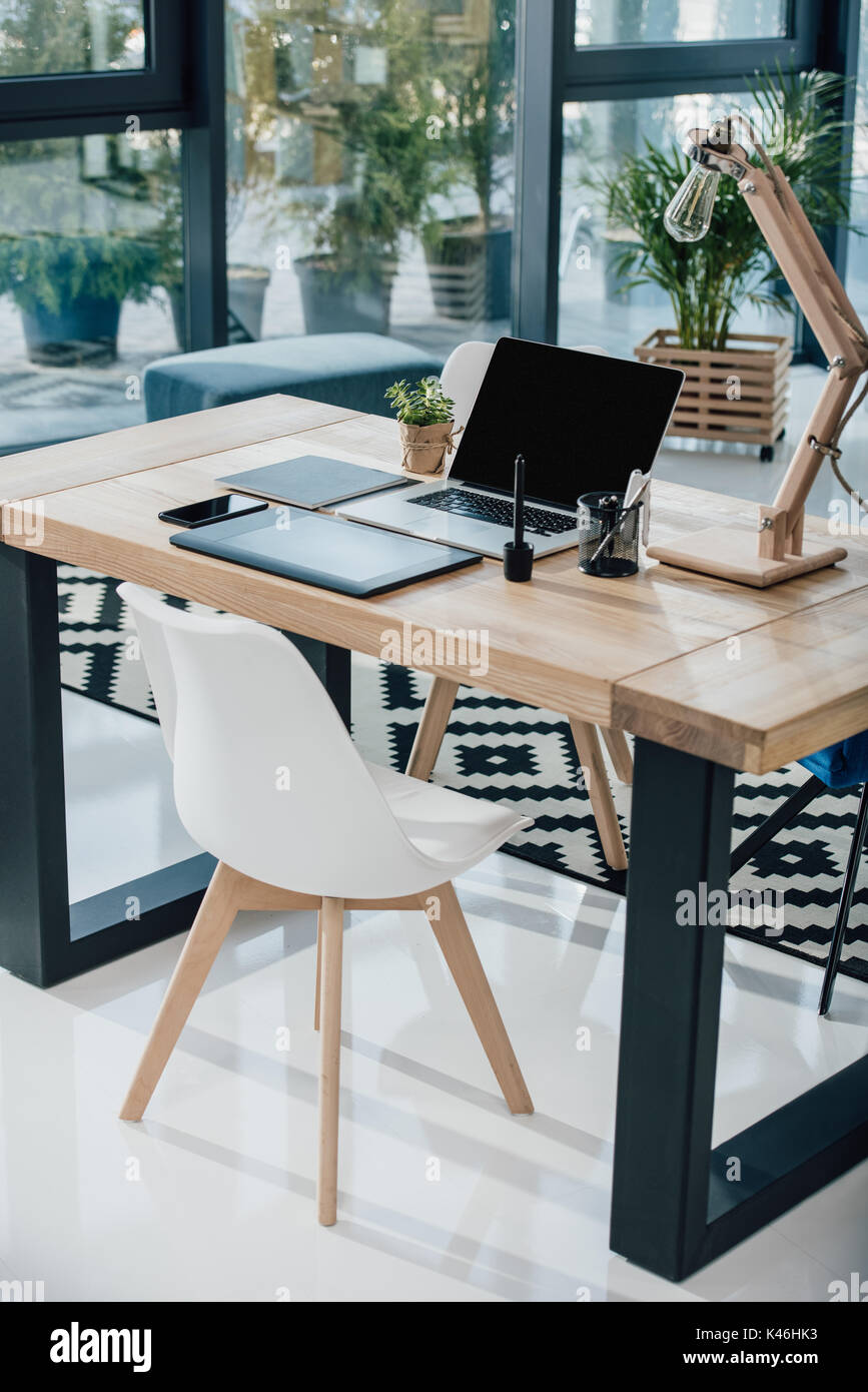 Computer portatile con schermo vuoto, graphic tablet e smartphone sul tavolo in ufficio moderno Foto Stock