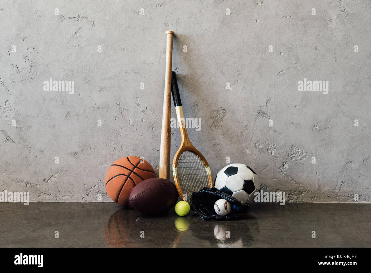 Vista ravvicinata di varie sfere e attrezzature sportive vicino al muro grigio Foto Stock