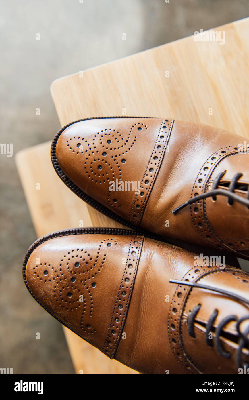 Close up di pelle marrone scarpe oxford su uno sgabello in legno Foto Stock