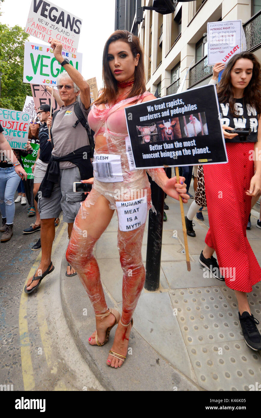 Attivisti per i diritti degli animali che protestavano a Piccadilly, Londra. Ragazza Shapely con sangue finto e pellicola trasparente codice a barre come un pezzo di carne. Attivista femmina Foto Stock