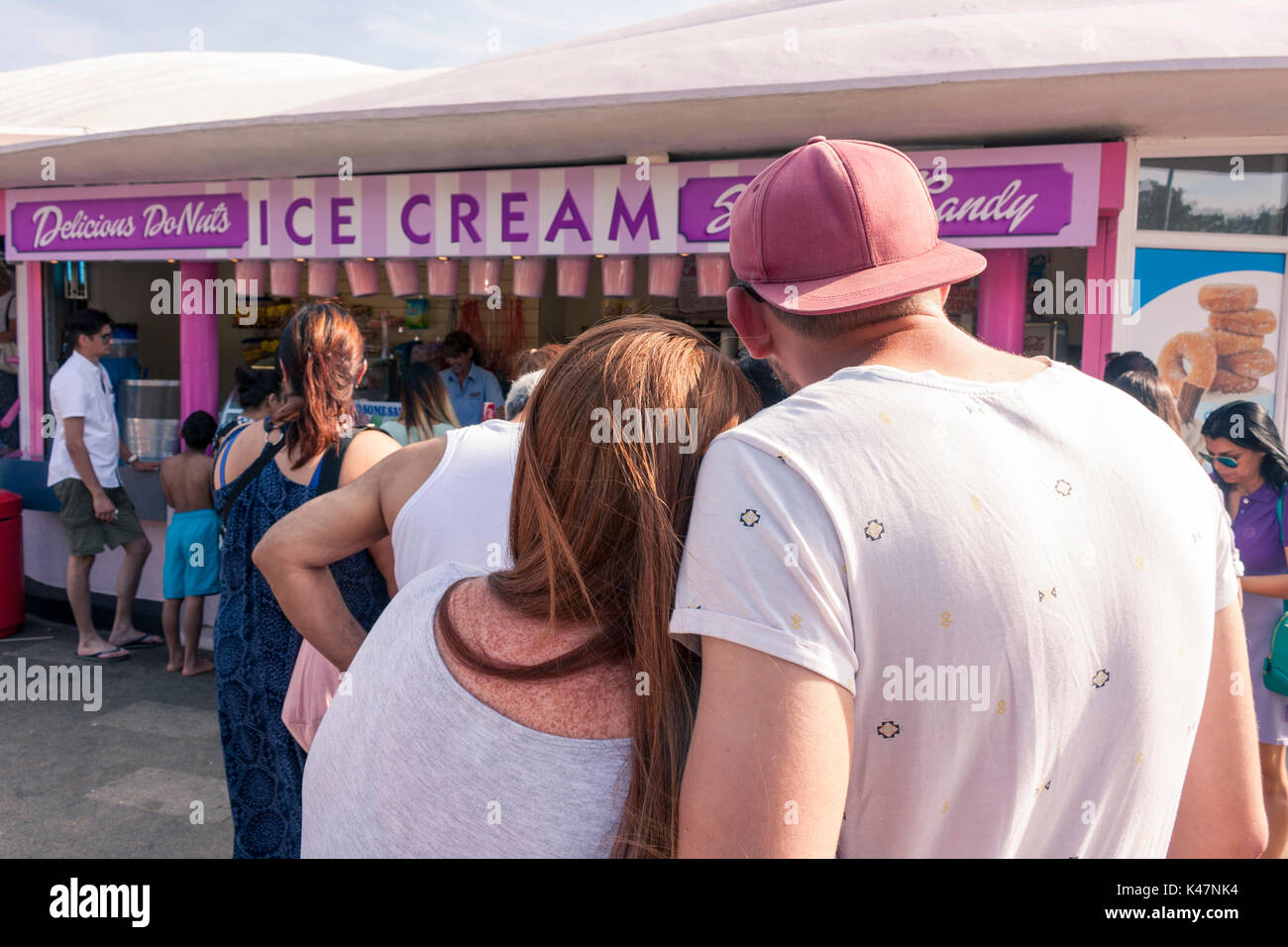 Vista posteriore di una giovane coppia in attesa in un gelato in stallo. Southend-on-Sea, Essex, Regno Unito Foto Stock