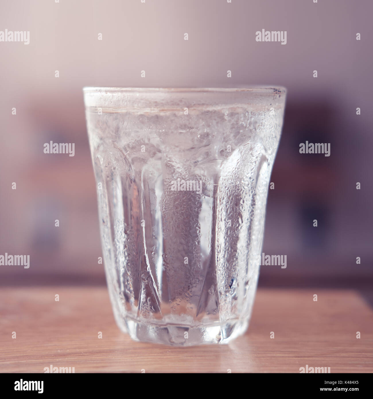 Bicchiere di acqua con ghiaccio sulla tavola di legno. Cromo Classico e stile vintage. Foto Stock