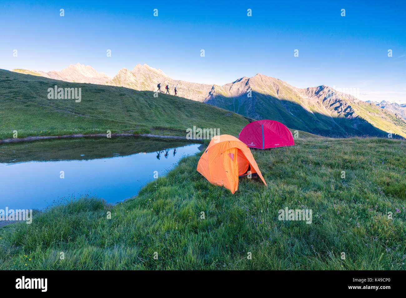 Sagome di escursionisti sono riflesse nel lago con Mont De La Saxe sullo sfondo Courmayeur Valle d'Aosta Italia Europa Foto Stock