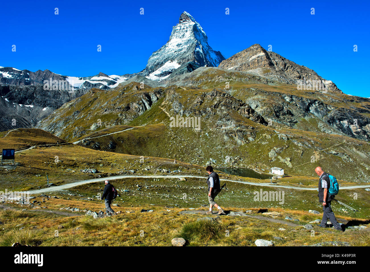 Tre turisti nell'area escursionistica attorno a Zermatt, il Lago Schwarzsee e Cervino dietro, Zermatt, Vallese, Svizzera Foto Stock