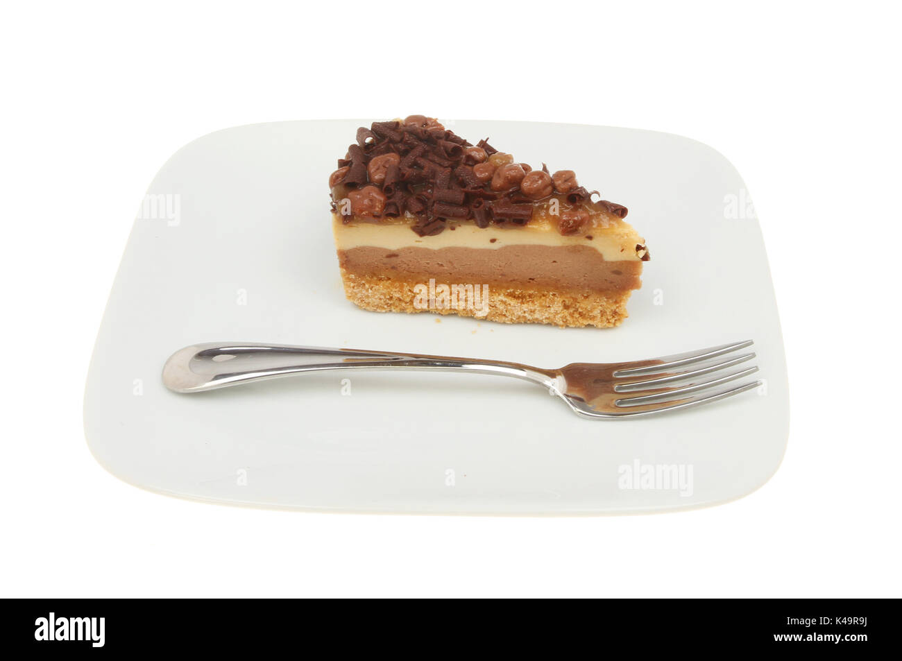 Fetta di cioccolato e nido cheesecake su una piastra con una forcella isolata contro bianco Foto Stock
