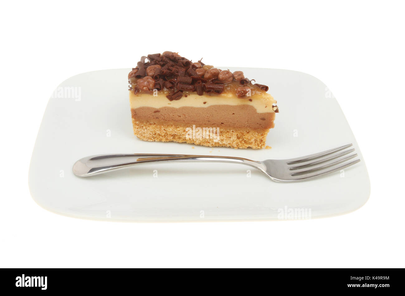 Fetta di cioccolato e nido cheesecake su una piastra con una forcella isolata contro bianco Foto Stock