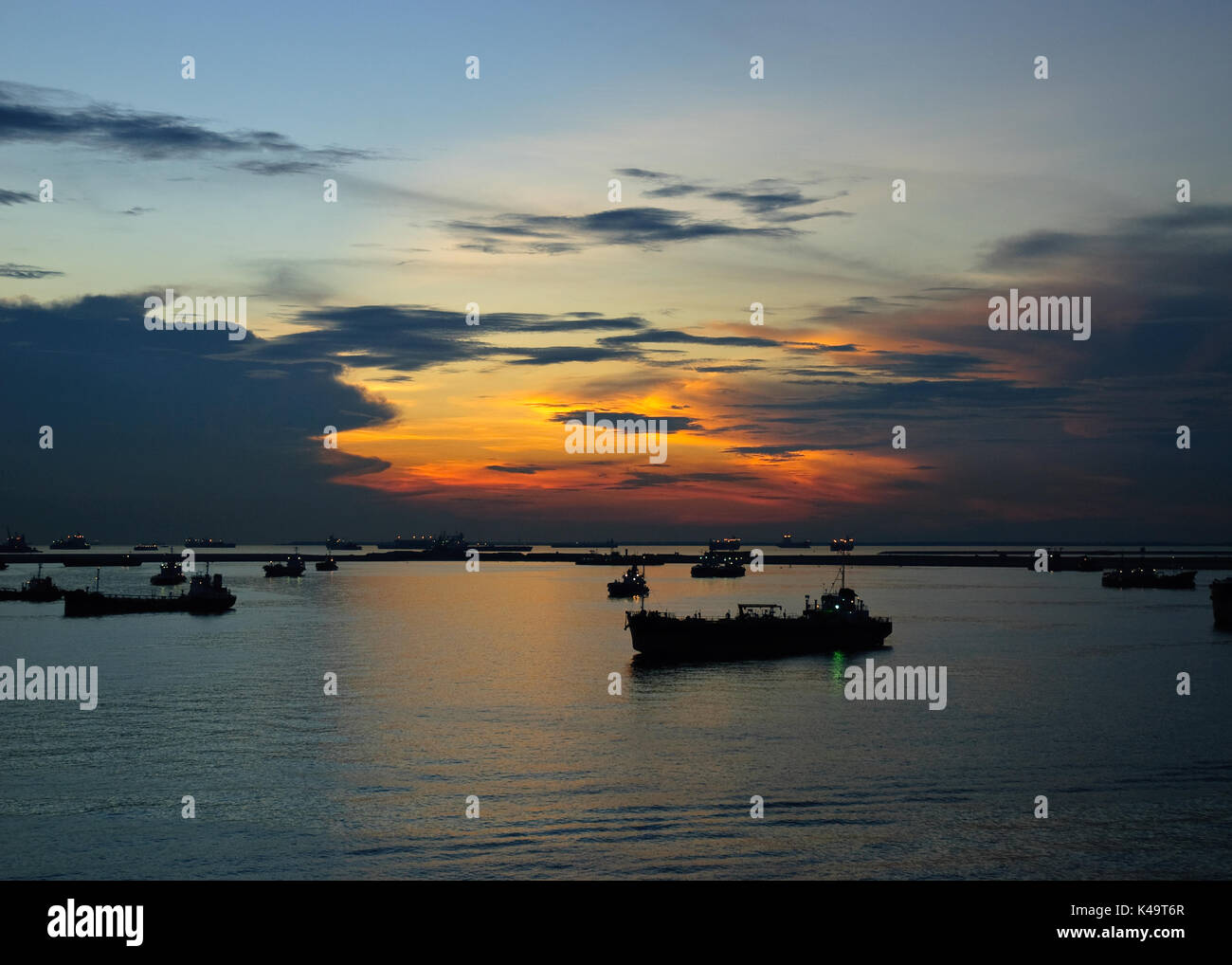 Le navi al tramonto a Singapore ancoraggio occidentale Foto Stock
