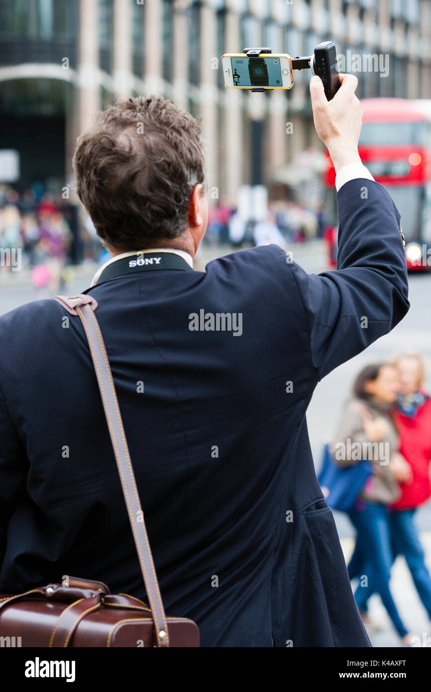 Londra, Regno Unito. Un uomo utilizza un gimble e un videofonino (r) al film Big Ben in piazza del Parlamento come suona il suo bongs finale per quattro anni. Foto Stock