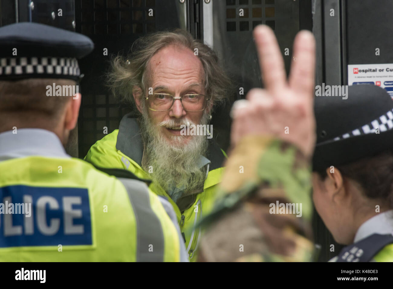 Londra, Regno Unito. 5 Sep, 2017. Sostenitori rallegrare e rendere 'V' per la vittoria di segni come un Quaker protester arrestati per seduta verso il basso per bloccare la strada nel mondo la più grande fiera di armi nelle Docklands di Londra è messo in un furgone della polizia. Il 'Nessuna fede in guerra " giorno di protesta è stata organizzata da vari gruppi di fede. Prima del mio arrivo vi era stato un lock-in sull'approccio road arrestando le consegne provenienti per impostare il giusto attraverso la porta est. Credito: Peter Marshall / Alamy Live News Foto Stock