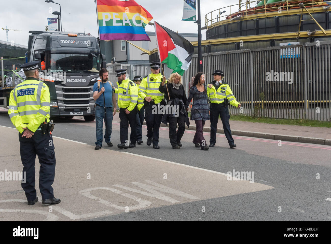 Londra, Regno Unito. 5 Sep, 2017. Gli ufficiali di polizia piombo manifestanti camminando lentamente con un flag nella parte anteriore di un autocarro fuori strada. I dimostranti sono stati il tentativo di fermare i camion che vanno verso il West Gate nel mondo la più grande fiera di armi detenute nelle Docklands di Londra fuori strada sullato 'Nessuna fede in guerra " giorno di proteste organizzate da diversi gruppi di fede. Prima del mio arrivo vi era stato un lock-in sull'approccio road arrestando le consegne provenienti per impostare il giusto attraverso la porta est. Credito: Peter Marshall / Alamy Live News Foto Stock