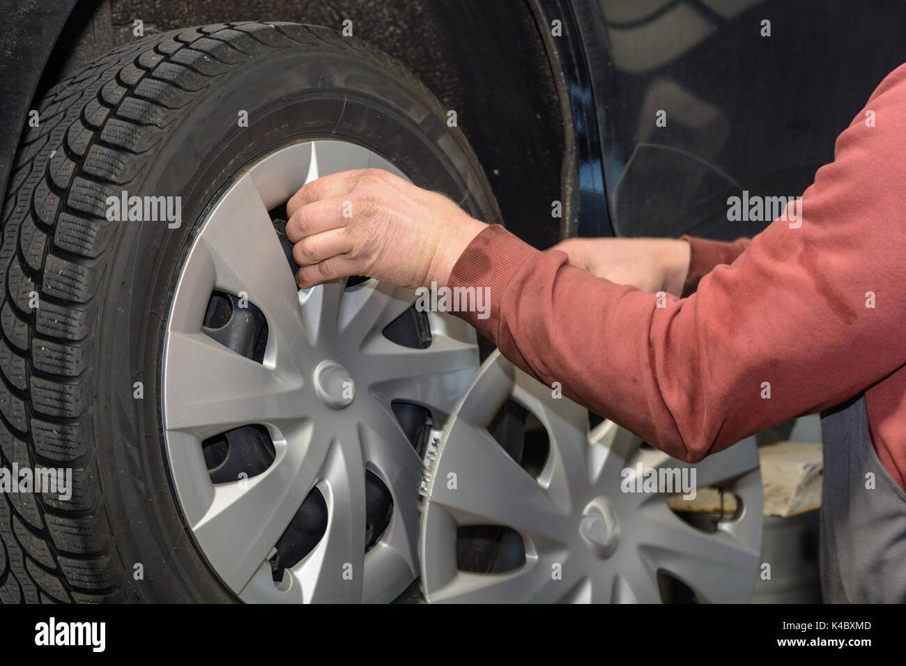 Mechanic rimuove il cappuccio del rivestimento a pneumatici per auto prima di una sostituzione di un pneumatico Foto Stock