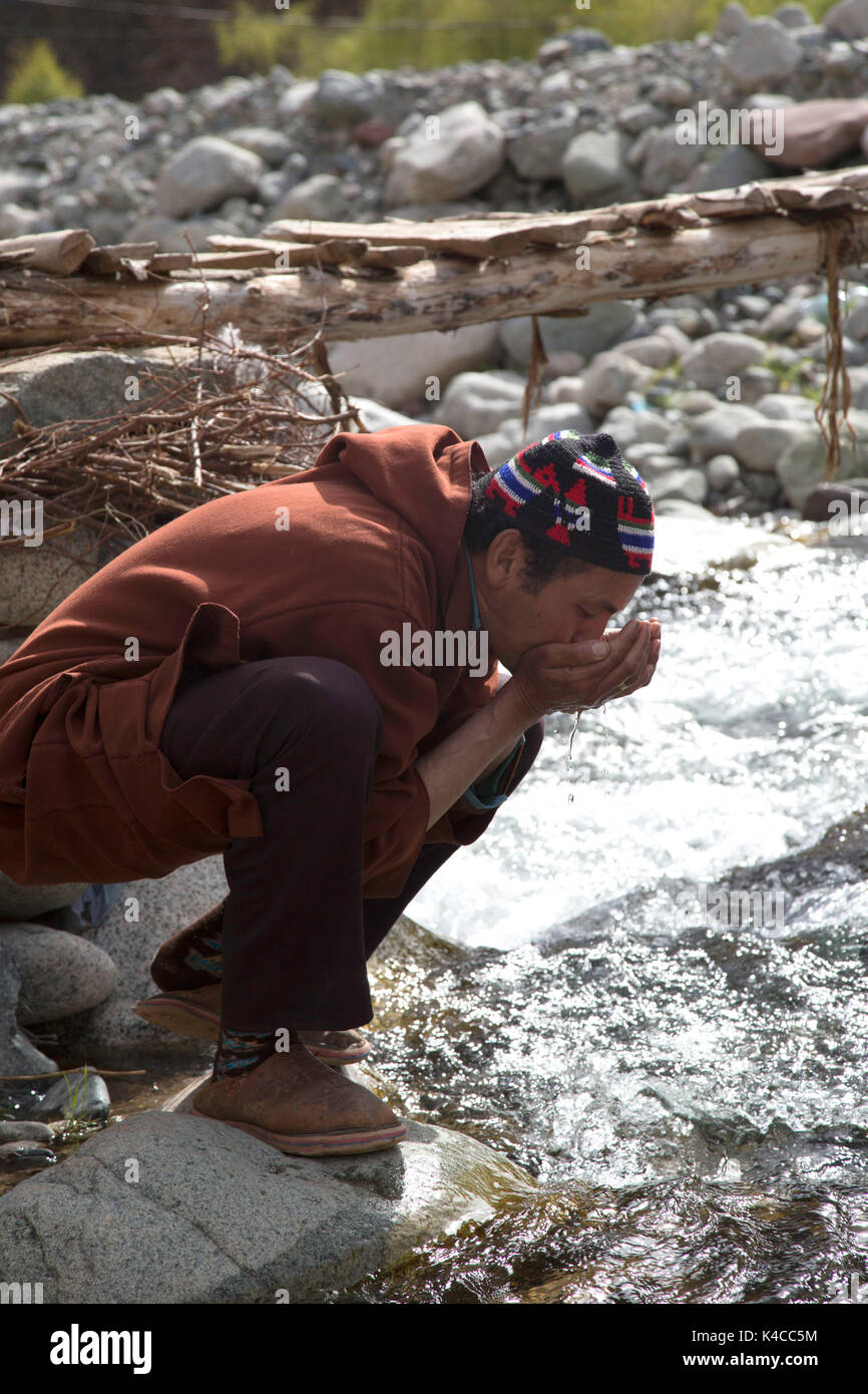 Berber l uomo beve dal fiume, setti fatma mercato, Ourika Valley, Marocco Foto Stock