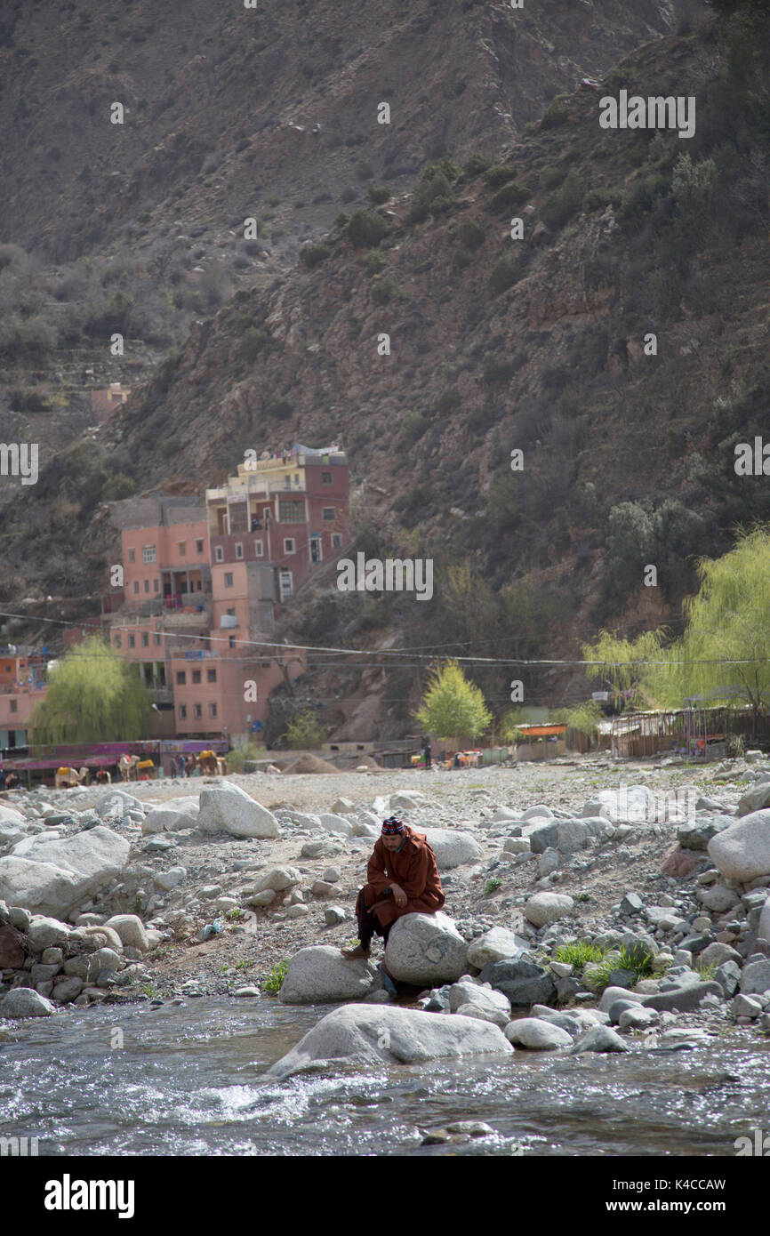 Berber uomo seduto da fiume, setti fatma, Ourika Valley, atlante, Marocco Foto Stock