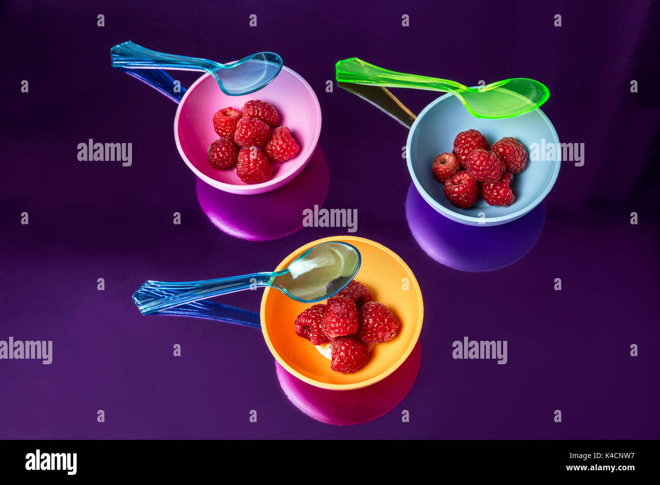 La moda dello sfondo con lamponi frutta rossa su contenitori multicolore e cucchiai Foto Stock