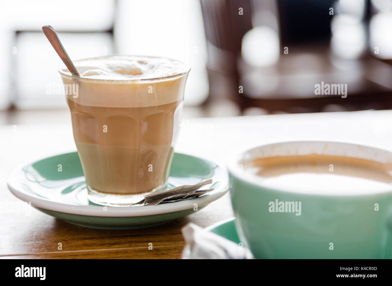 Caffè bianco in vetro transparentretro sul verde di pentola e tavolo in legno nel bar. Avviare un buon mattino. Chiudere la luce naturale raccolto Foto Stock