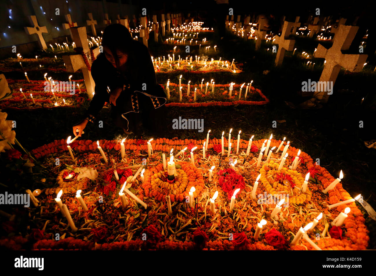 Una donna candele luci e metterli sulle tombe dei loro cari nel giorno della commemorazione di tutti i defunti nel novembre 02 al Santo Rosario chiesa cattolica a Dhaka, Ba Foto Stock