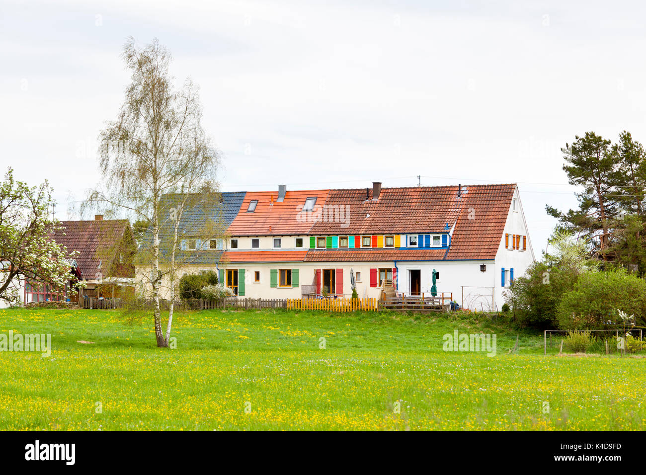 Una vecchia casa dietro un prato con persiane colorate su windows nella Germania meridionale. Foto Stock