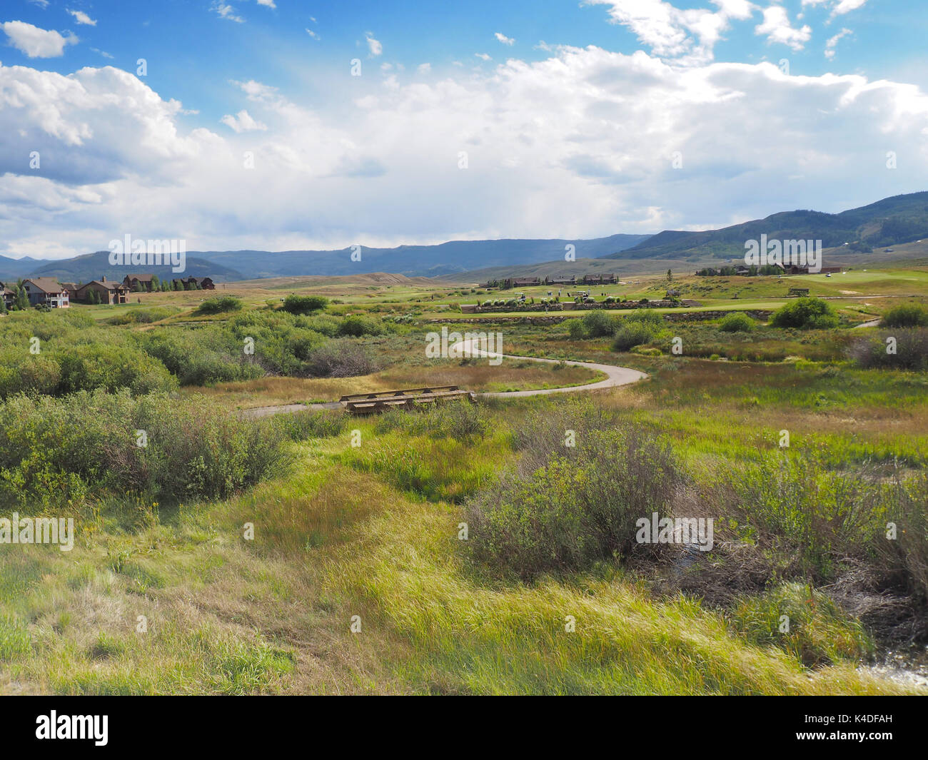 Un campo da golf su prairie in Colorado. Il corso è vicino a un alloggiamento di sviluppo. Ci sono montagne sullo sfondo e un cielo azzurro overh Foto Stock