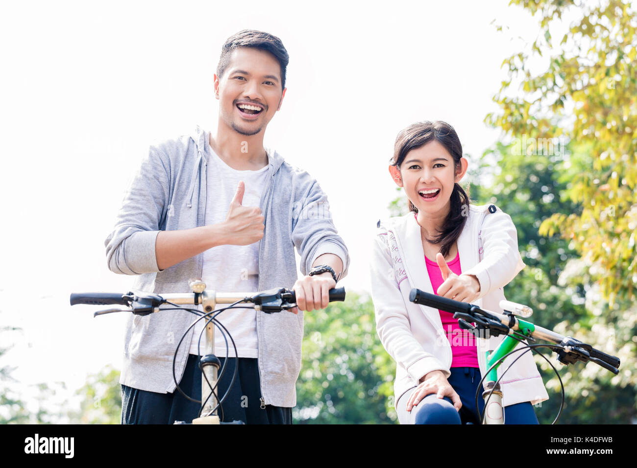 Giovani asiatici giovane ridere insieme mentre equitazione biciclette Foto Stock