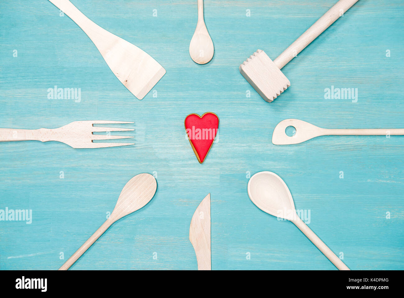 Vista superiore del legno di vari utensili da cucina con il simbolo del cuore blu sul piano portapaziente Foto Stock