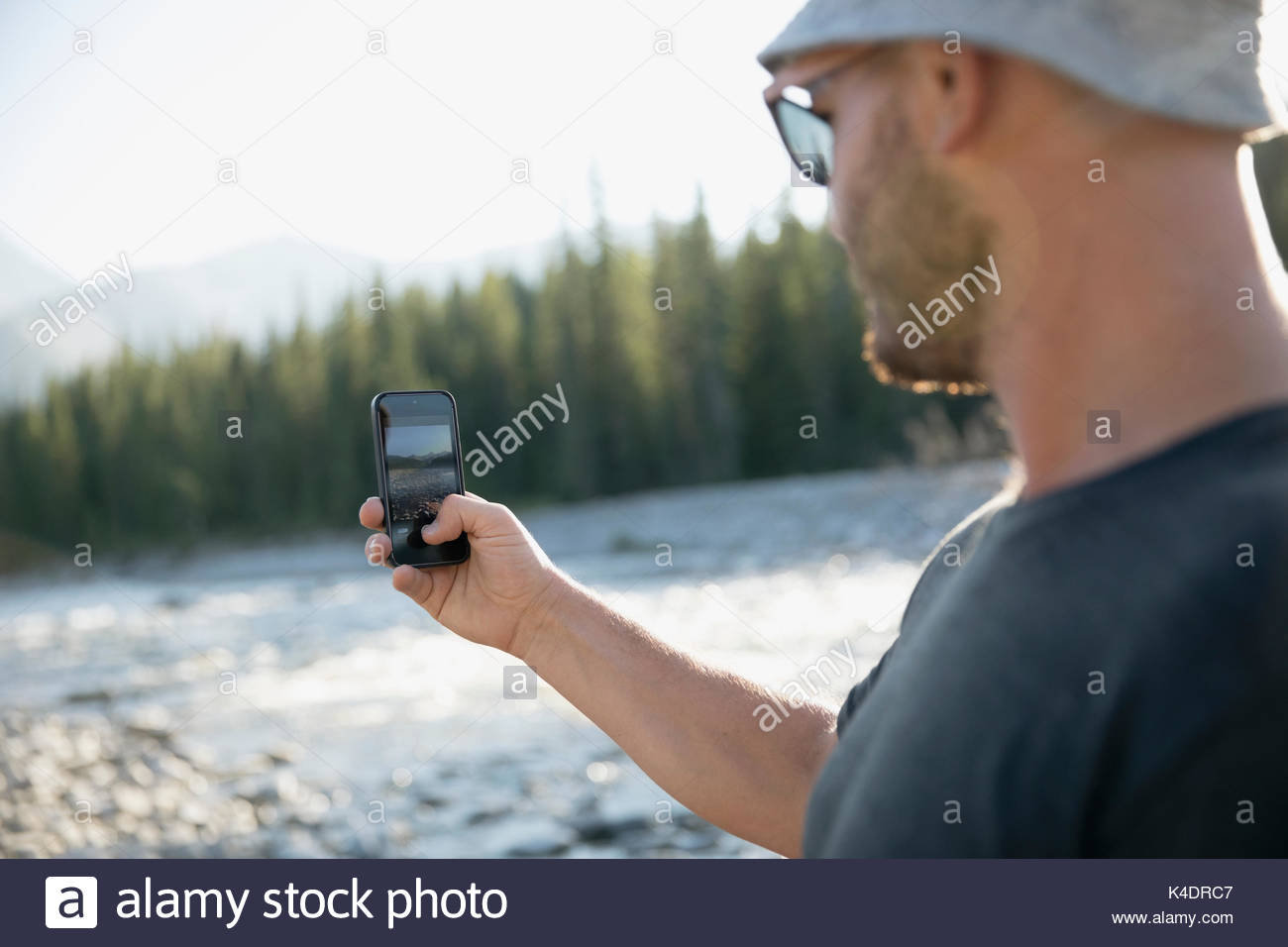 L'uomo escursionismo, tramite telefono con fotocamera, fotografando estiva soleggiata stream Foto Stock