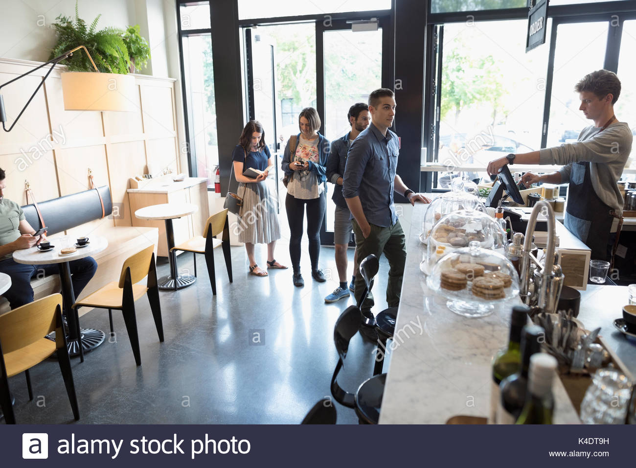 Lavoratore di sesso maschile aiutando i clienti in coda al cafe counter Foto Stock