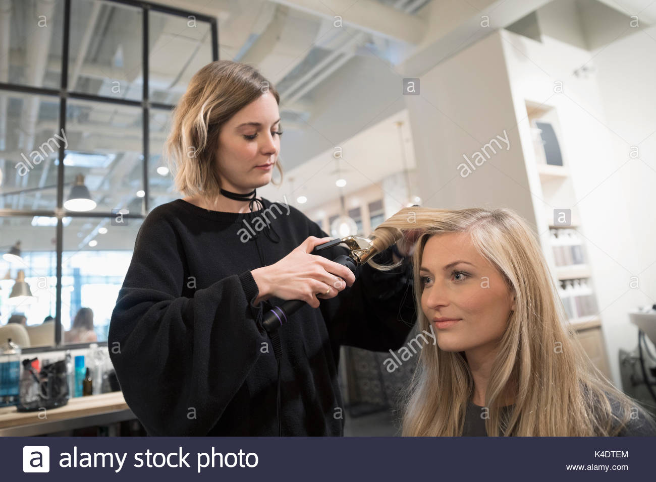 Femmina hair stylist arricciamento dei capelli del cliente con ferro arricciacapelli in parrucchiere Foto Stock