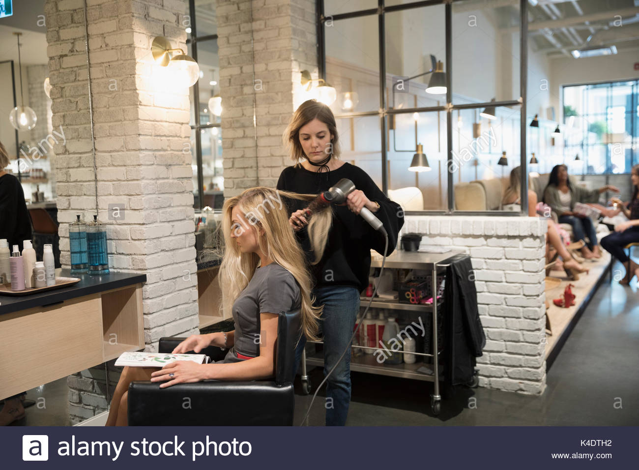 Femmina hair stylist soffiare l'asciugatura dei capelli del cliente nel salone di parrucchiere Foto Stock