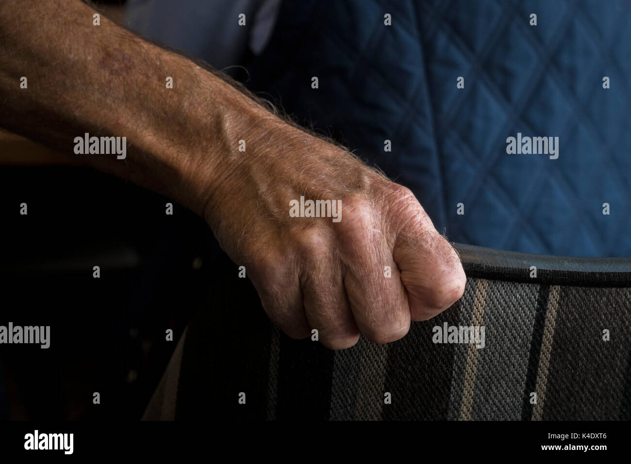 Età - una vista ingrandita della mano di una persona anziana saldamente la presa sullo schienale di una sedia. Foto Stock