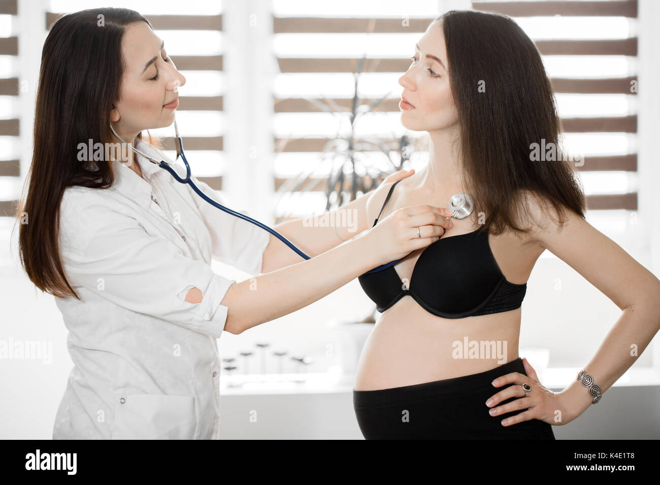 Medicina femminile medico tenendo stetoscopio per donna incinta in piedi  per l'incoraggiamento, empatia, allietarla,supporto, visita medica. La  nuova vita di un Foto stock - Alamy