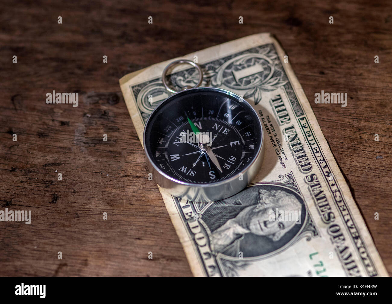Bussola di navigazione sulla parte superiore di un dollaro e un background in legno, il denaro e il concetto di direzione Foto Stock