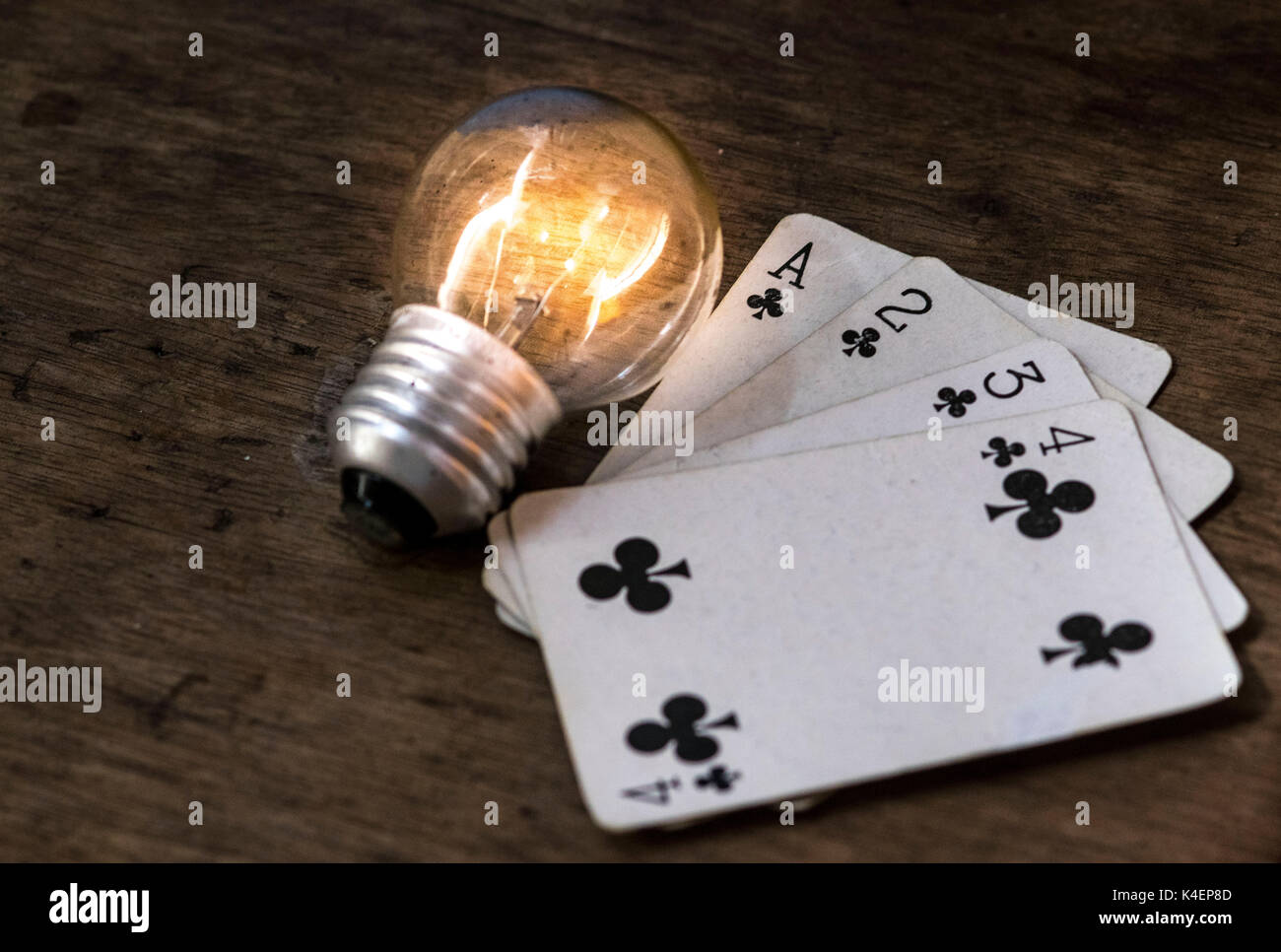 Accende la lampadina della luce bianca e giocare a carte a faccia in su sulla parte superiore di una superficie di legno, gioco d'azzardo e vincendo il concetto idea Foto Stock