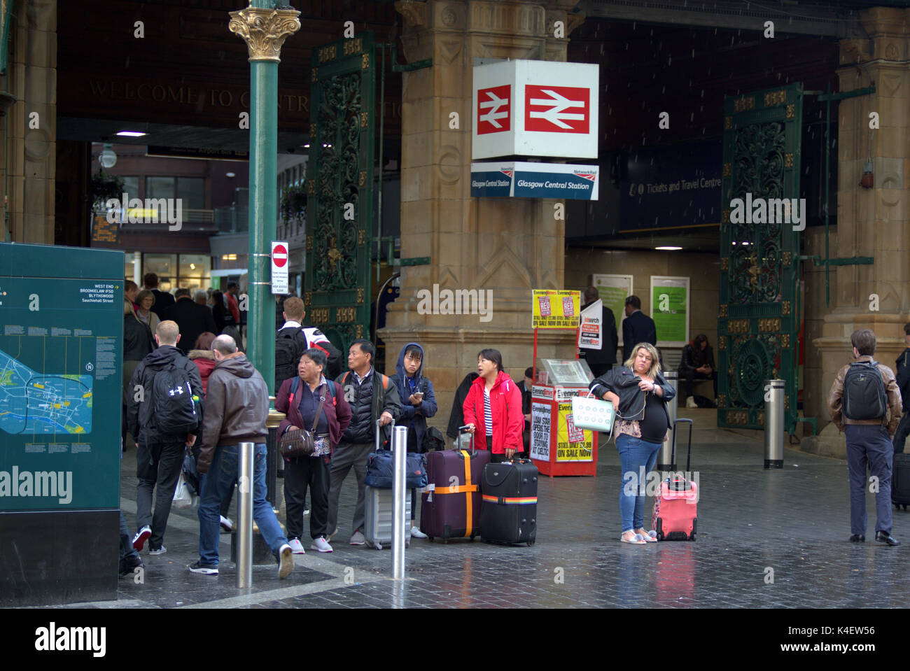 La stazione centrale di ingresso anteriore posizione taxi ingresso anteriore vicino a Hope Street Glasgow wet turisti cinesi con trolley casi in attesa di taxi in caso di pioggia Foto Stock