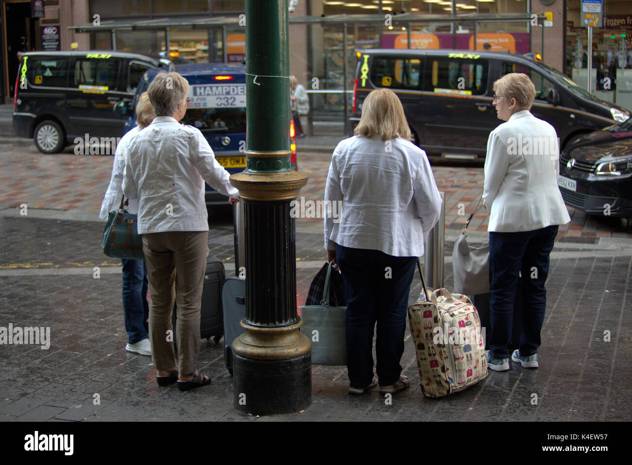 Stazione centrale di entrata anteriore taxi atteggiamento hotspot inquinamento ingresso anteriore vicino a Hope Street Glasgow ladies con trolley casi in attesa di taxi Foto Stock