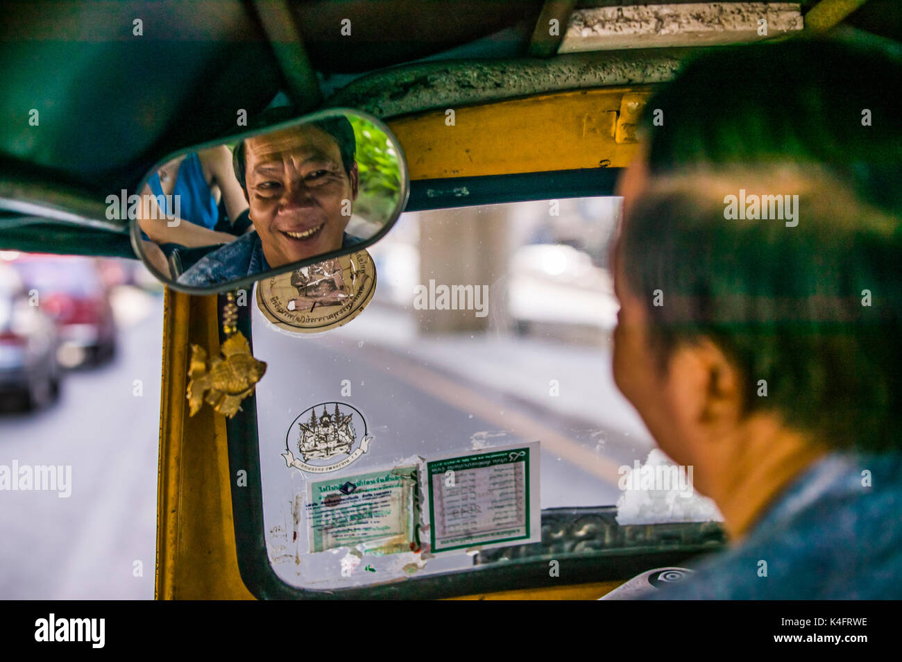 Un sorridenti Tuk Tuk driver visto nel suo specchietto retrovisore, Bangkok, Thailandia. Foto Stock
