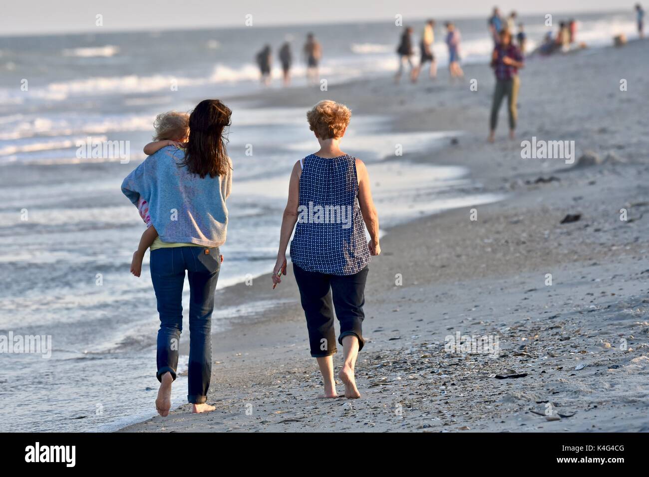 Famiglia camminando giù ocean beach Foto Stock