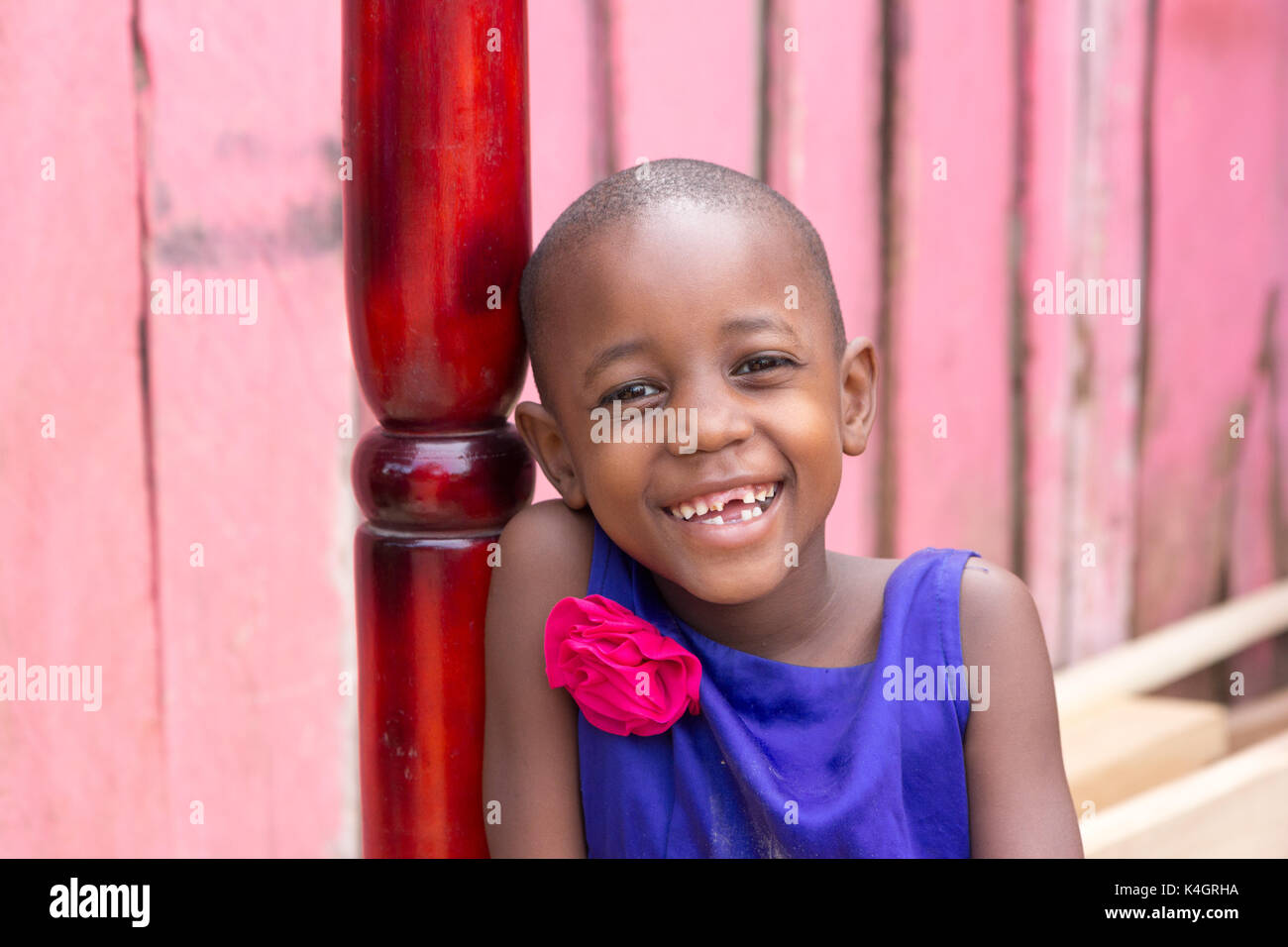 Una giovane e bella ragazza sorridente. Ella è vestito con un abito blu con fiore rosa sulla spalla. Foto Stock