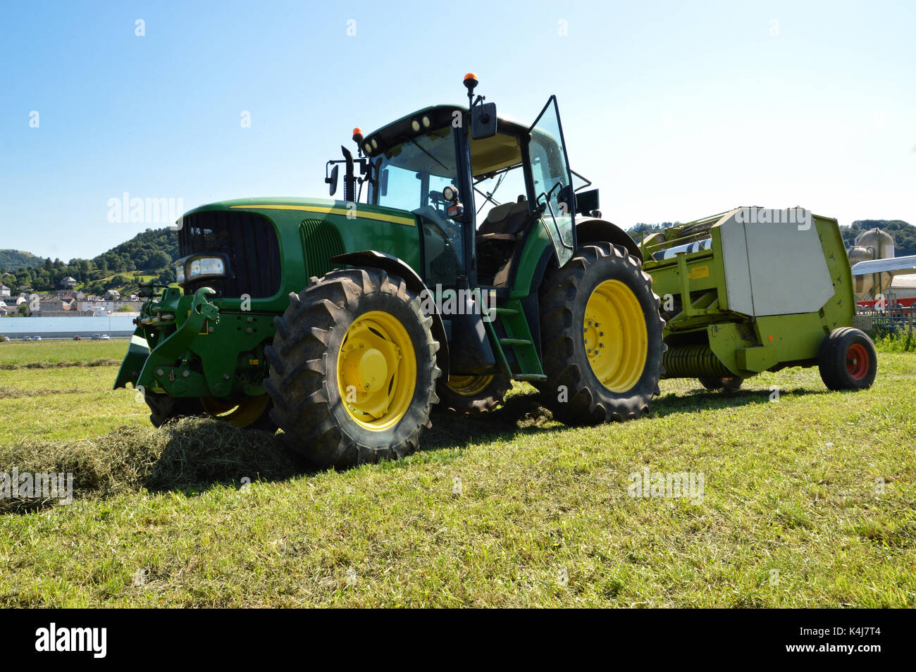 Un trattore agricolo con un'imballatrice per la raccolta di paglia e fieno. (Paglia e fieno balle) Foto Stock